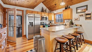 Una cocina moderna con armarios de madera, electrodomésticos de acero inoxidable y una isla central con taburetes de bar.