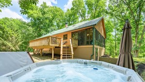 Un jacuzzi con una terraza de madera y una casa con ventanas amplias.