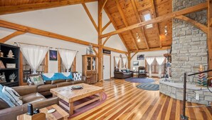 Un salón amplio con un alto techo de madera, una chimenea de piedra y un acogedor conjunto de asientos.
