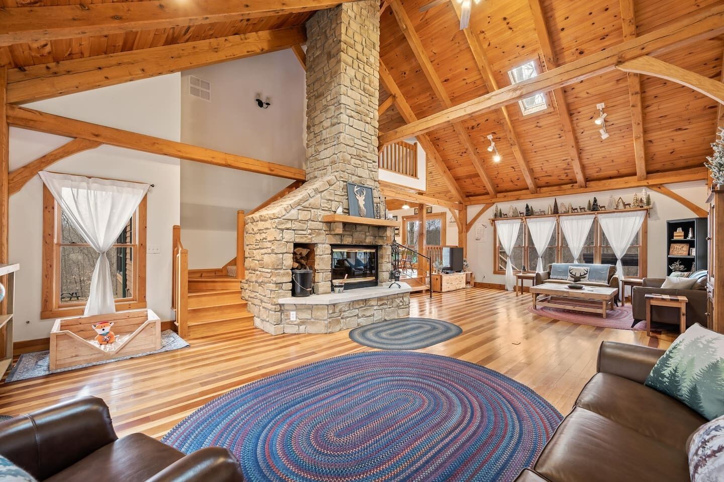 A spacious living area with a stone fireplace, wooden beams, and a cozy seating arrangement.