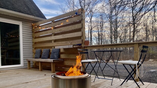 Una terrazza con un braciere in metallo, panche di legno e un tavolo con sedie.