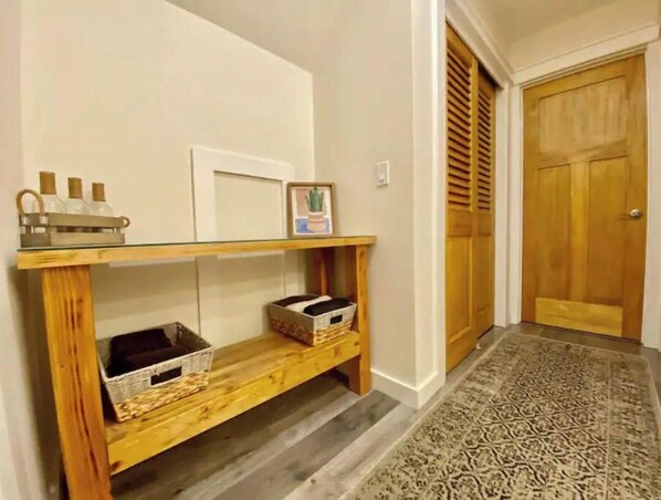 A hallway with a wooden console table, baskets, and a patterned rug.