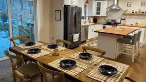 Una cucina moderna con mobili bianchi, un frigorifero nero e un tavolo da pranzo in legno con sottopiatti.