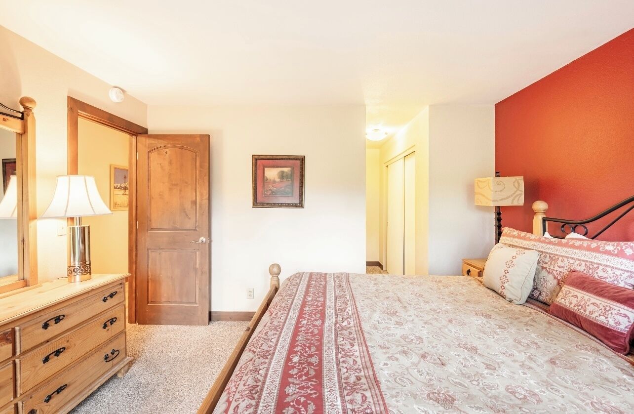 A bedroom with a bed, wooden dresser, and a door.