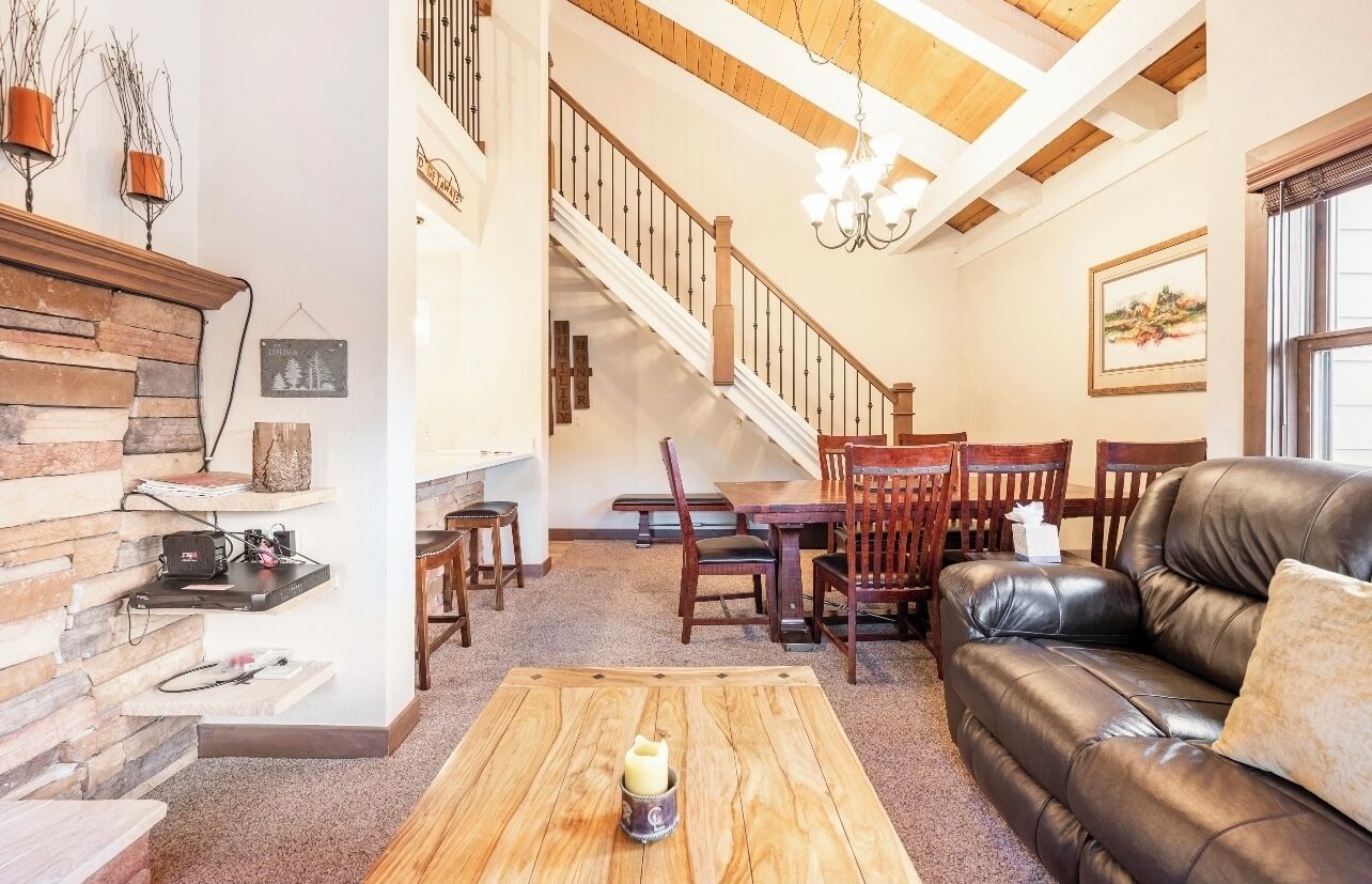 A spacious living room with a staircase, wooden furniture, and a chandelier.