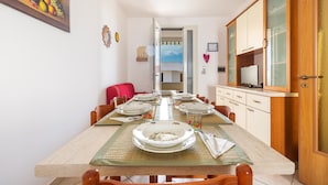 A dining area with a long table set for six, chairs, a ceiling fan, a painting, and a cabinet with a television. - 2468 Casa Sofia by Barbarhouse (Ugento)
