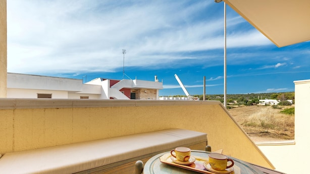 A balcony with a cushioned bench and a table with two cups and saucers. - 2468 Casa Sofia by Barbarhouse (Ugento)