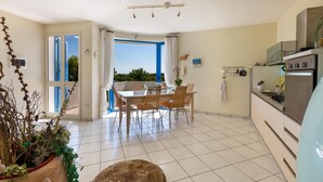 A modern kitchen with a built-in oven and microwave, a dining area with a table and chairs, and a view through a glass door to the outside. - 2539 Casa di Isa by Barbarhouse (Castrignano del Capo)