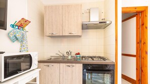 A compact kitchen with a microwave, stove, oven, and wooden cabinets. - 2369 Mono Le Rose by Barbarhouse (Ugento)