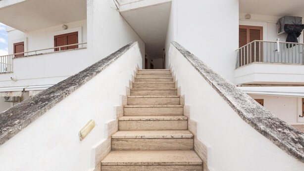 A staircase leading to a second-floor balcony with a white wall and a metal railing. - 2369 Mono Le Rose by Barbarhouse (Ugento)