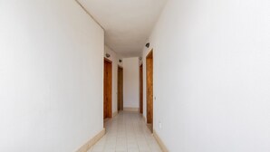 A narrow hallway with white walls and a tiled floor, leading to wooden doors at the end. - 2369 Mono Le Rose by Barbarhouse (Ugento)