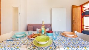 A dining area with a table set for two, featuring a patterned tablecloth, various dishes, and a bottle of wine. - 2369 Mono Le Rose by Barbarhouse (Ugento)