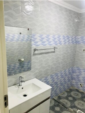 Bathroom features a sink, mirror, towel rack, and toilet, set against a textured tile backdrop.