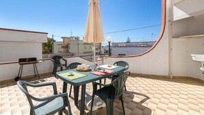 A rooftop terrace with a table, chairs, and an umbrella. - 2810 Case al Tacco - Appartamento Mare by Barbarhouse (Castrignano del Capo)