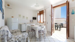 A compact living space with a dining area, kitchenette, and a view to an outdoor patio. - 2810 Case al Tacco - Appartamento Mare by Barbarhouse (Castrignano del Capo)