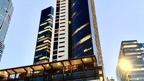 Un moderno grattacielo dal design verticale distintivo, con un rivestimento che combina vetro e metallo.