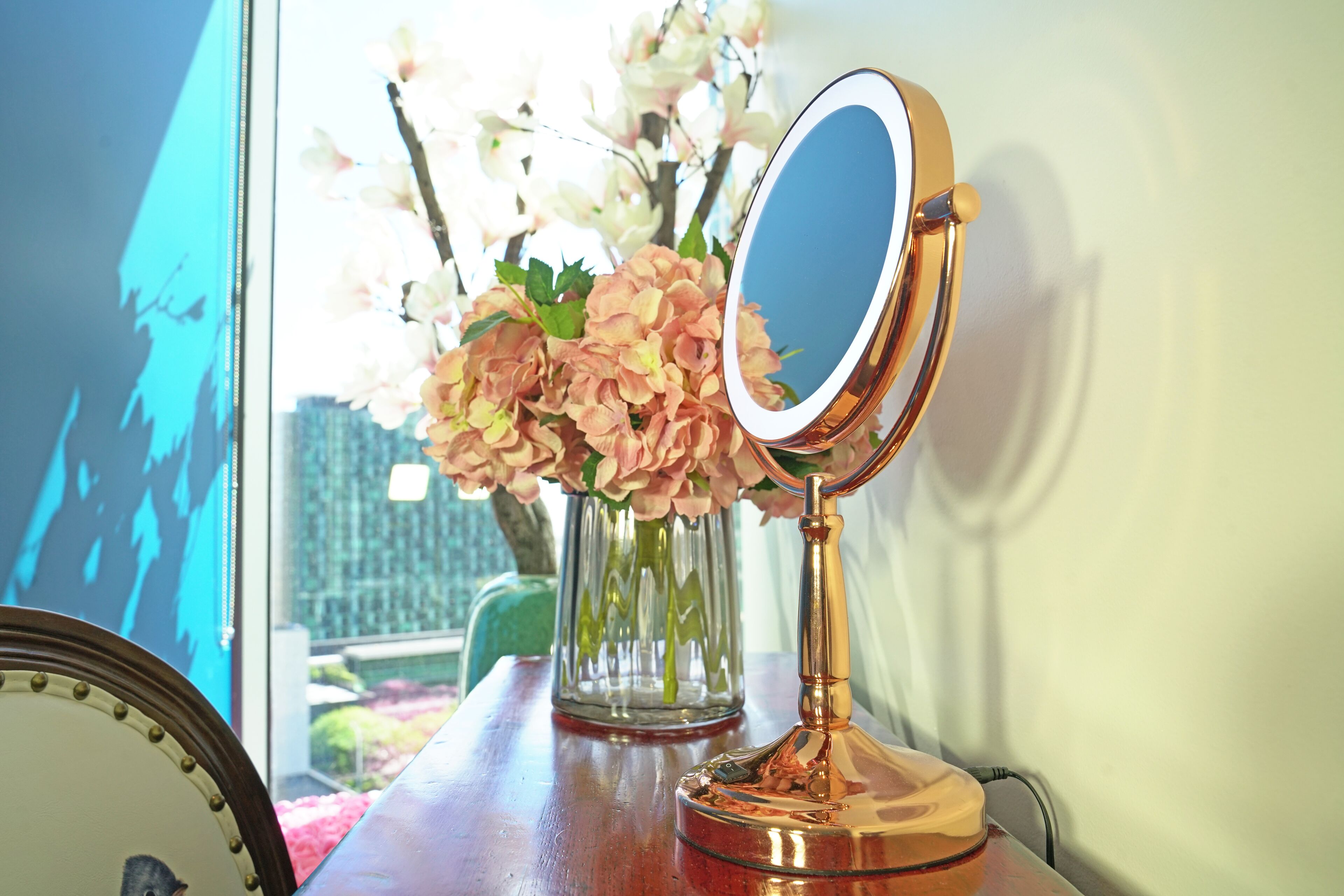 A wooden table with a mirror, a vase with flowers, and a framed picture.