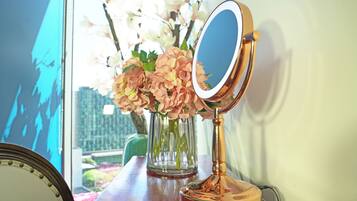 A wooden table with a mirror, a vase with flowers, and a framed picture.