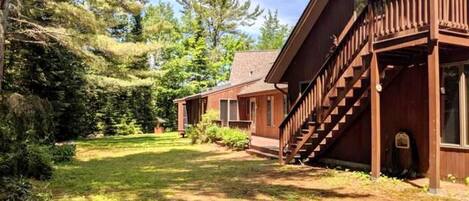 A cabin with a wooden exterior, a covered porch, and a staircase leading to the entrance.