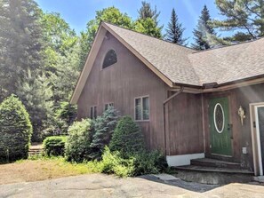 A wooden house with a green door, surrounded by dense greenery and trees. - Charming Guest House & King Suite - Twin Mountain River Retreat (Carroll)