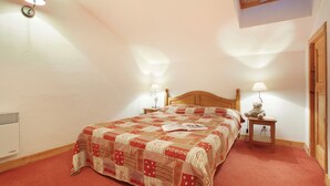 A bedroom with a bed, two bedside tables with lamps, a window, and a ceiling fan.