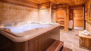 Un interior de madera con una bañera de hidromasaje, bancos de madera y una pared de azulejos.