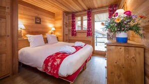 Una habitación de cabaña de madera con una cama, un aparador y una ventana con cortinas.
