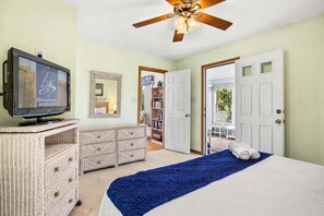 A bedroom with a bed, a television, a ceiling fan, a dresser, and a door leading to a balcony. - A Peace of Quiet | 1,025 ft. to the Beach | Private Pool (Duck)