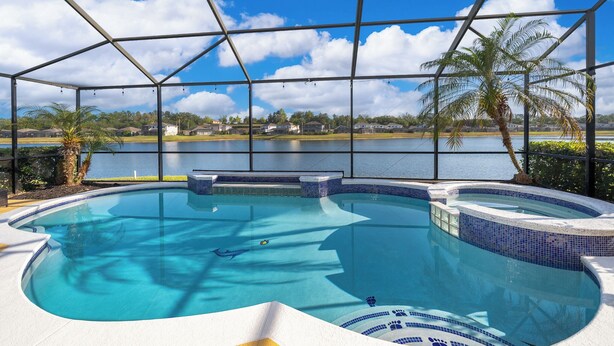 Uma piscina com vista para um lago e casas ao fundo.