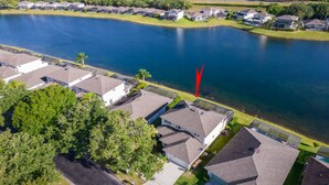 Zona residencial com casas perto de um lago, com vista clara para a água e vegetação ao redor.