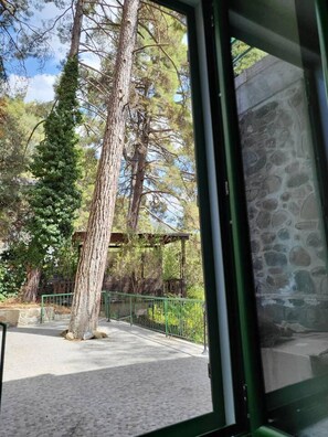 A stone building with a paved walkway and a green fence. - Theplatresnest Lovely 3-bed House in Pano Platres (Platres)