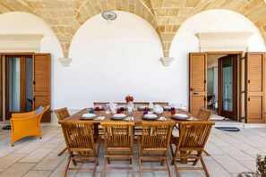 A dining area with a round table set for six, surrounded by wooden chairs.