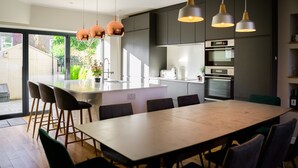 Una cocina moderna con una isla central, muebles oscuros e iluminación colgante.