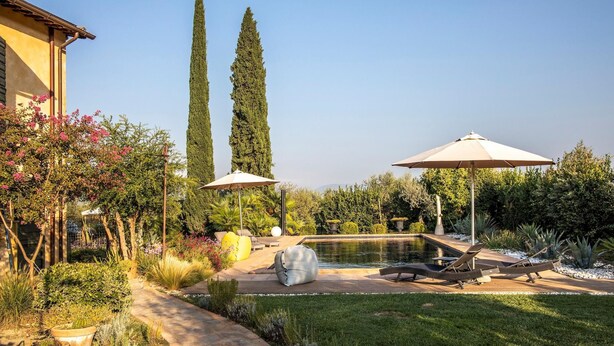 A well-maintained garden with a swimming pool, lounge chairs, and umbrellas. - Casale Santa Lucia 8 2 (Bettona)