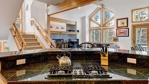 A kitchen with a granite countertop, a gas stove, and a kettle. There is a wooden staircase leading to an upper level. - Downtown WP Villa 491 I Great Views I Loft With Desk I Discounted Attractions (Winter Park)
