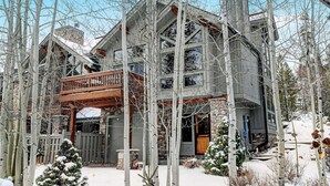 A multi-story wooden house with a balcony, surrounded by snow-covered trees. - Downtown WP Villa 491 I Great Views I Loft With Desk I Discounted Attractions (Winter Park)