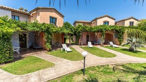 A courtyard with multiple buildings, outdoor seating, and greenery. - Two-room apartment with 4 beds, (38 sq m): living room with kitchenette, table fridge and double sofa bed, double bedroom (beds can be separated), bathroom. <br>They can be on the ground floor with a patio or on the 1st floor with a balcony, both equippe (Pula)