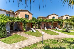 Un patio con varios edificios, mobiliario exterior y vegetación.