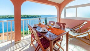Un comedor con una mesa dispuesta para dos personas, con vistas a un cuerpo de agua y tierra a lo lejos.