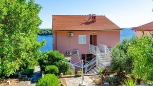 Una villa rosa con techo de tejas rojas, una escalera y vista al mar.
