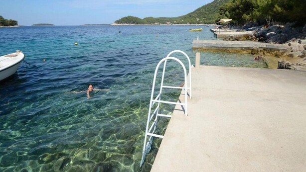 Un paisaje marítimo despejado con un muelle de hormigón, una escalera y un bote.