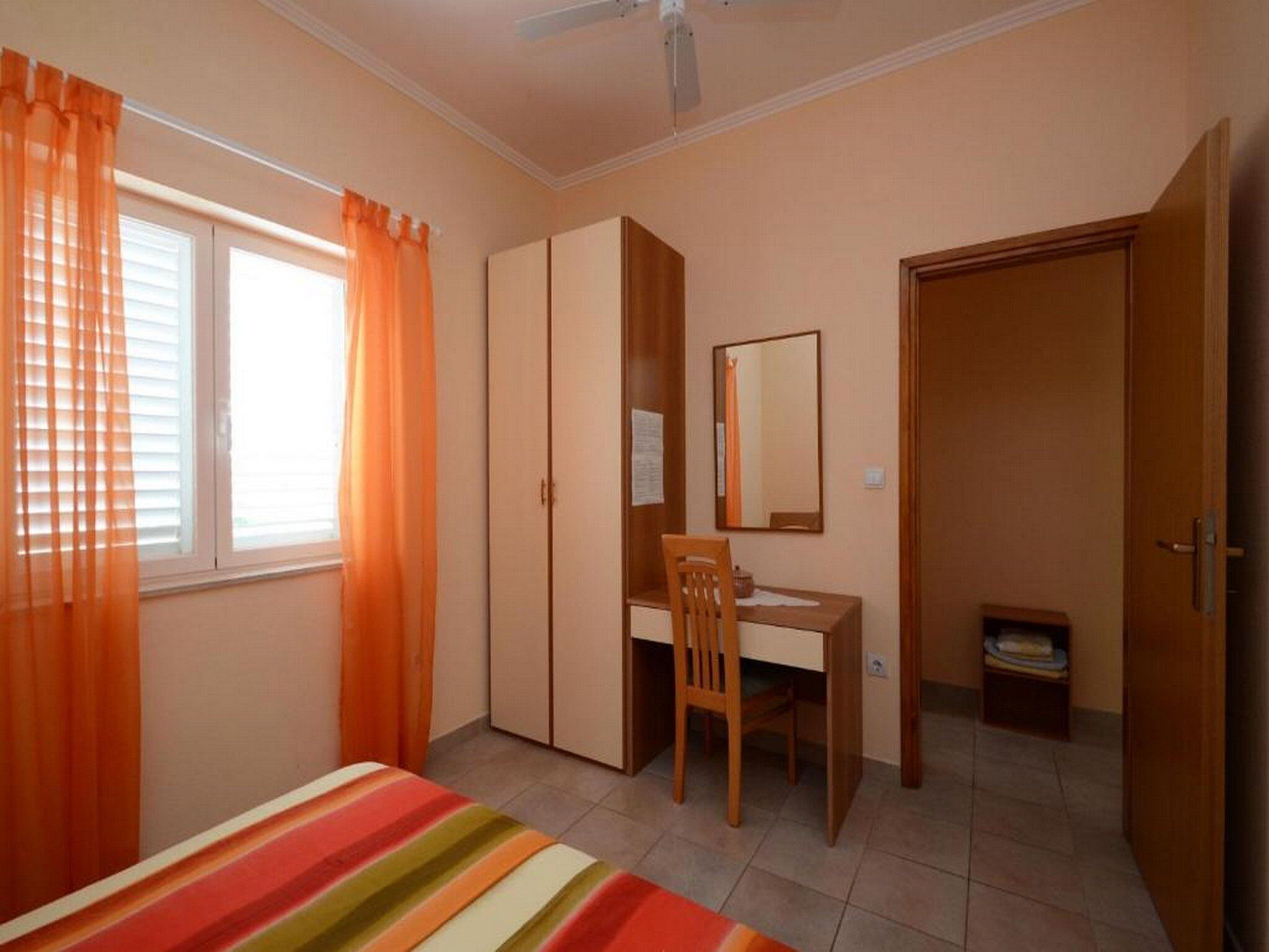 A bedroom with a bed, a desk, a chair, a wardrobe, and a door.
