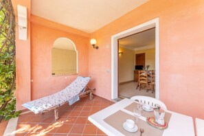 A room with a bed, a table set for two, and a doorway leading to a dining area.