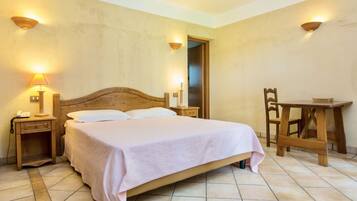 A bedroom with a wooden bed, two bedside tables with lamps, a wooden chair, and a small table.