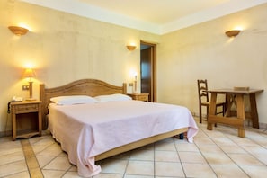 A bedroom with a wooden bed, two bedside tables with lamps, a wooden chair, and a small table.