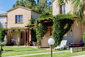 Una casa con patio, area salotto esterna e giardino curato.