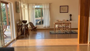 A spacious living area with a wooden ceiling, a dining table with chairs, a sofa, and a coffee table. - Stunning spacious suite with amazing views! (Halfmoon Bay)