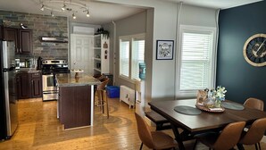 Una cocina moderna con una isla central, suelo de madera y un comedor con mesa y sillas.