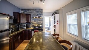 Una cocina moderna con armarios de madera oscura, un refrigerador de acero inoxidable, un microondas empotrado y una isla grande con encimera oscura.