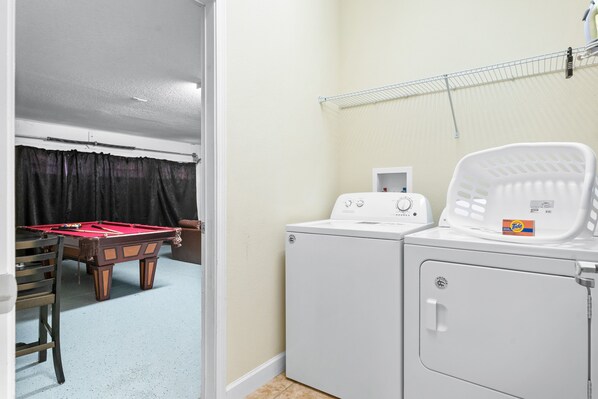 A laundry room with a washing machine, dryer, and a pool table.